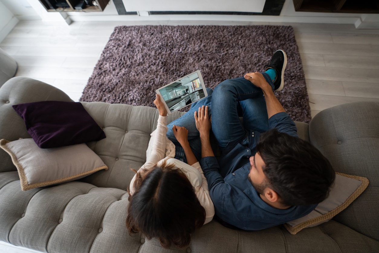 A couple sits on their couch and takes a virtual home tour, while engaging with an AI chatbot for more information.