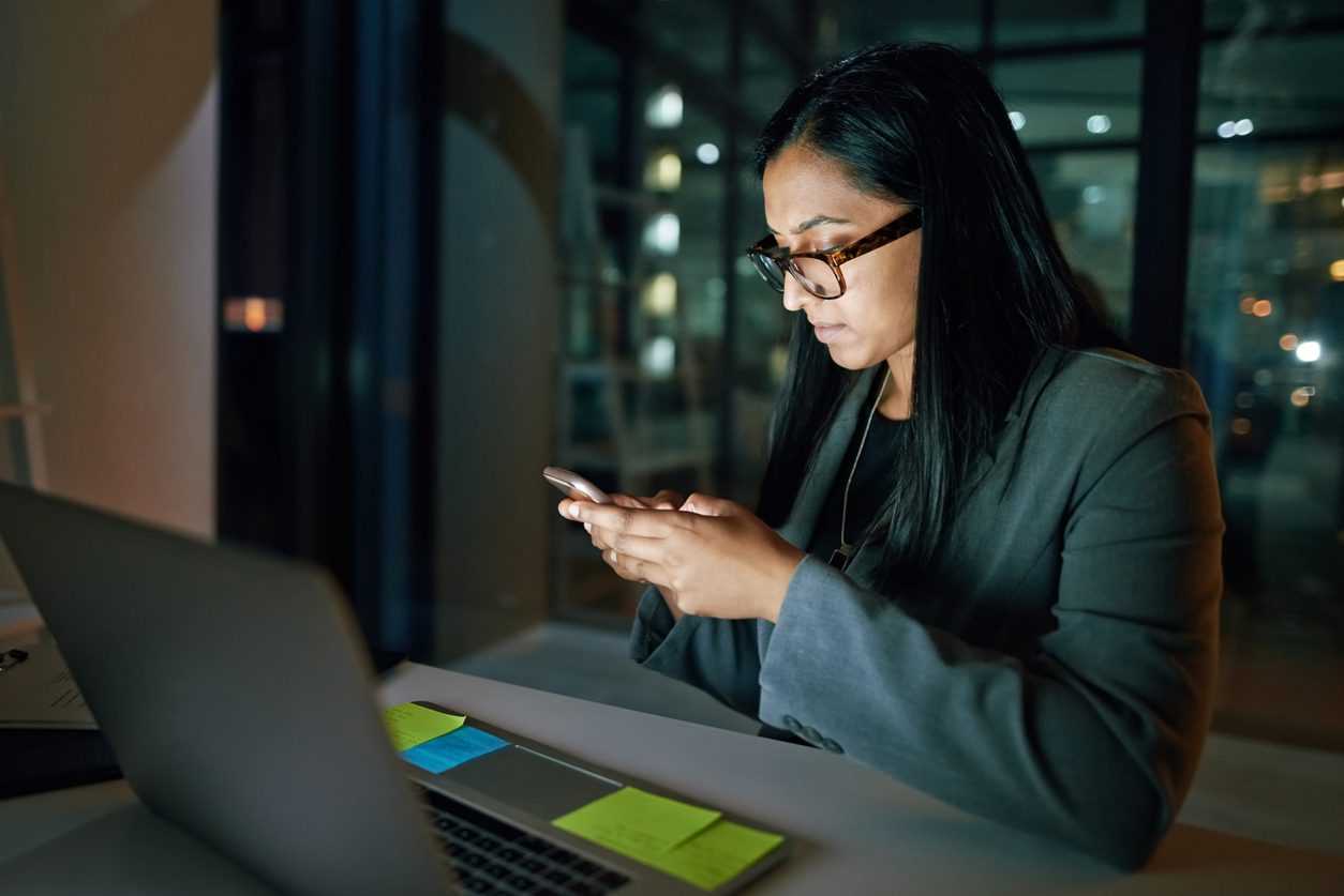 A woman sits at her computer at night researching homes for sale while an AI-powered chatbot responds to her inquiries as part of an AI for homebuyer engagement strategy.